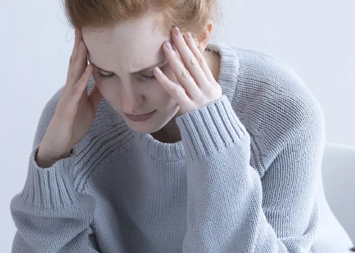 Woman holding her head in distress – PTSD therapy in London